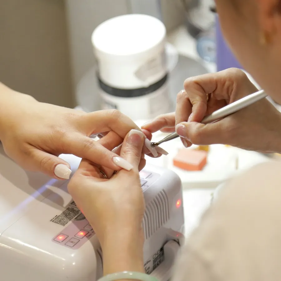Nail designer finalizando unhas em gel na cabine de luz